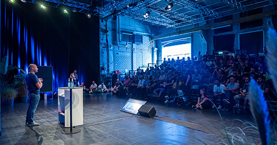 Man is speaking on stage of auditorium
